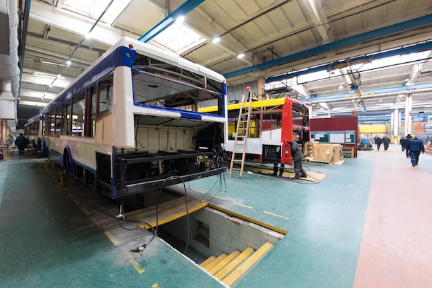 Un día de trabajo de fabricación de autobuses automáticos modernos con trabajadores de automóviles sin terminar con antecedentes de piezas de automóviles uniformes de protección