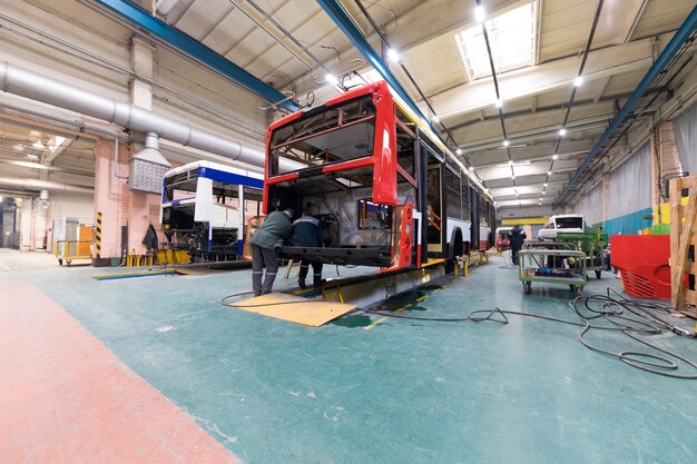 Un día de trabajo de fabricación de autobuses automáticos modernos con trabajadores de automóviles sin terminar con antecedentes de piezas de automóviles uniformes de protección