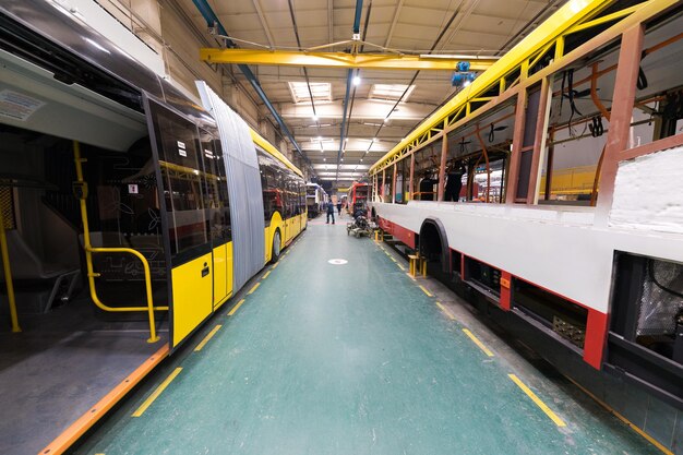 Un día de trabajo de fabricación de autobuses automáticos modernos con trabajadores de automóviles sin terminar en la industria automotriz uniforme de protección