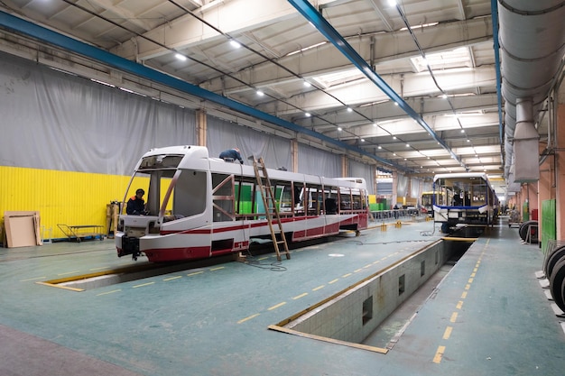 Un día de trabajo de la producción automática moderna de automóviles de trolebuses con trabajadores de automóviles sin terminar con uniforme protector en la línea de ensamblaje de automóviles de fondo automotriz