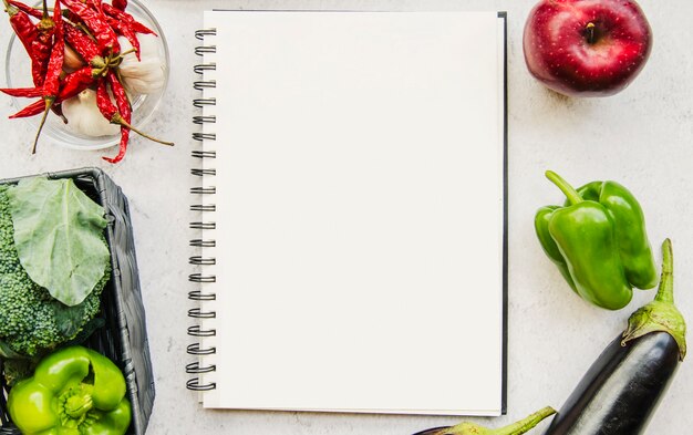 Diario vacío y verduras frescas sobre fondo blanco
