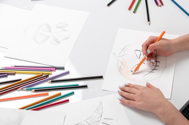 Dibujar a mano una niña dibujando una calabaza de halloween con lápiz naranja