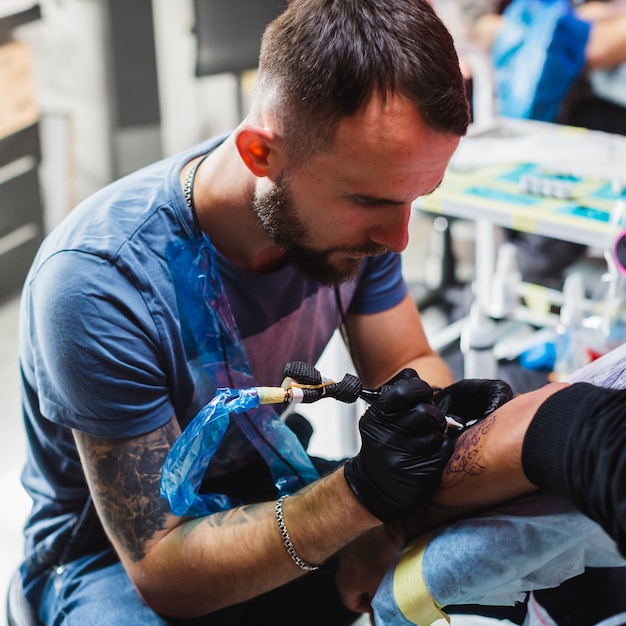 Dibujo maestro tatuaje en el brazo del cliente