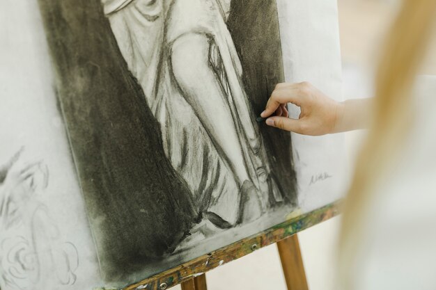 Dibujo de mano del artista femenino con lienzo en el caballete