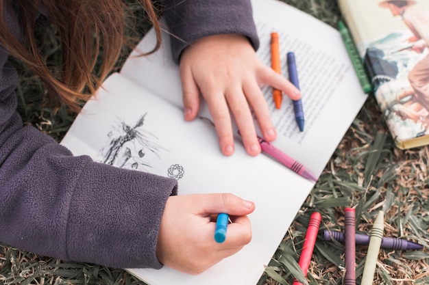 Dibujo de niña de cultivo en el cuaderno en el suelo