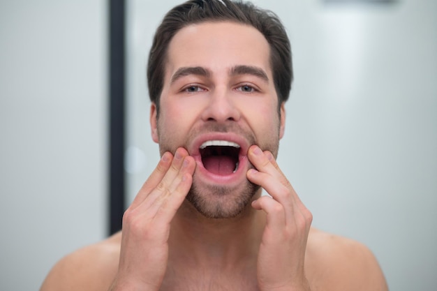 Dientes sanos. Hombre con la boca abierta examinando sus dientes