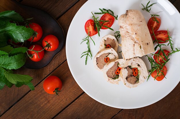 Dieta al horno rollos de pollo rellenos de hígado, chile y hierbas con una ensalada de tomates y rúcula. Menú dietético Nutrición apropiada. Vista superior