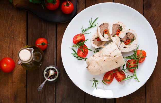 Dieta al horno rollos de pollo rellenos de hígado, chile y hierbas con una ensalada de tomates y rúcula. Menú dietético Nutrición apropiada. Vista superior