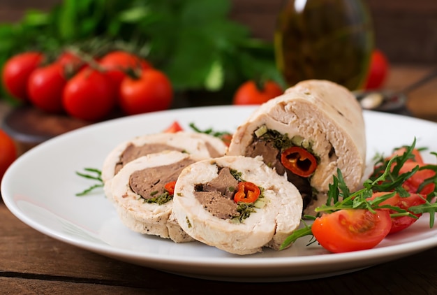 Dieta al horno rollos de pollo rellenos de hígado, chile y hierbas con una ensalada de tomates y rúcula. Menú dietético Nutrición apropiada.