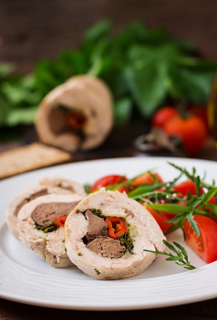 Dieta al horno rollos de pollo rellenos de hígado, chile y hierbas con una ensalada de tomates y rúcula. Menú dietético Nutrición apropiada.