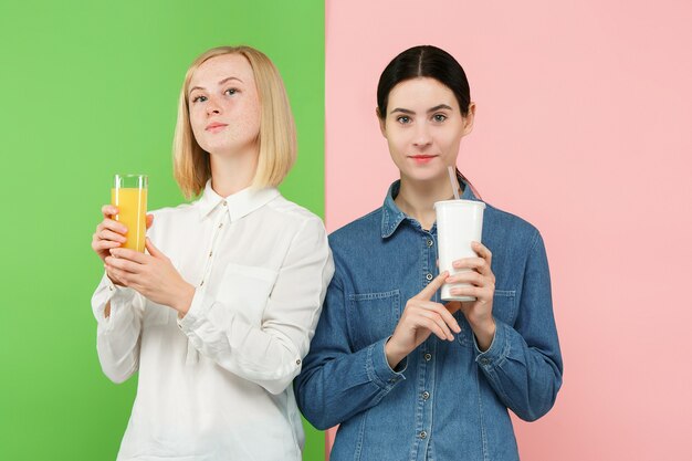 Dieta. Concepto de dieta. Comida sana. Hermosas mujeres jóvenes eligiendo entre jugo de naranja y bebida dulce carbonatada poco saludable