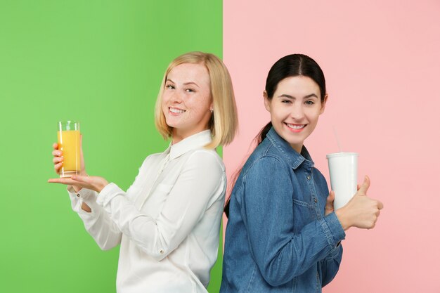 Dieta. Concepto de dieta. Comida sana. Hermosas mujeres jóvenes que eligen entre zumo de naranja y bebidas no carbonatadas dulces