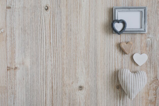 Diferentes corazones y un marco blanco sobre una mesa de madera