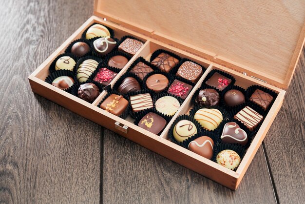 Diferentes dulces de chocolate en caja de madera.