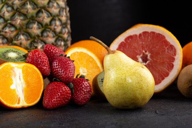 Diferentes frutas frescas maduras suaves jugosas medio corte aislado en escritorio oscuro