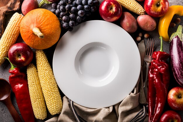 Diferentes frutas y hortalizas de otoño de temporada con placa vacía sobre fondo gris