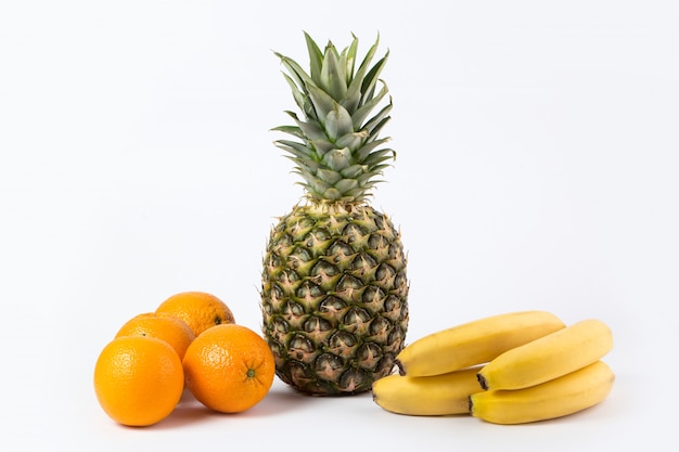 Diferentes frutas ricas en vitaminas maduras naranjas y plátanos de piña aislados en un piso blanco