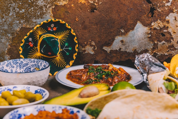 Foto gratuita diferentes platillos mexicanos deliciosos sobre fondo oxidado con sombrero mexicano