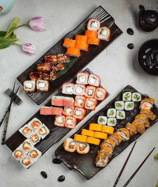 Diferentes rollos de variedad con palillos en un plato negro.