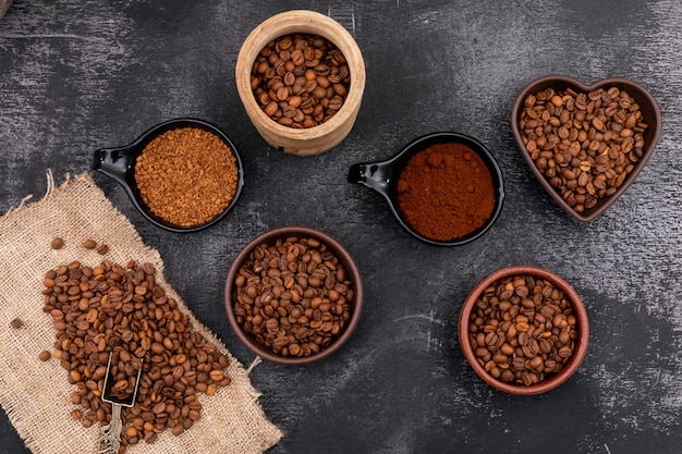 Foto gratuita diferentes tipos de café en tazón de madera de cerámica sobre superficie de madera negra