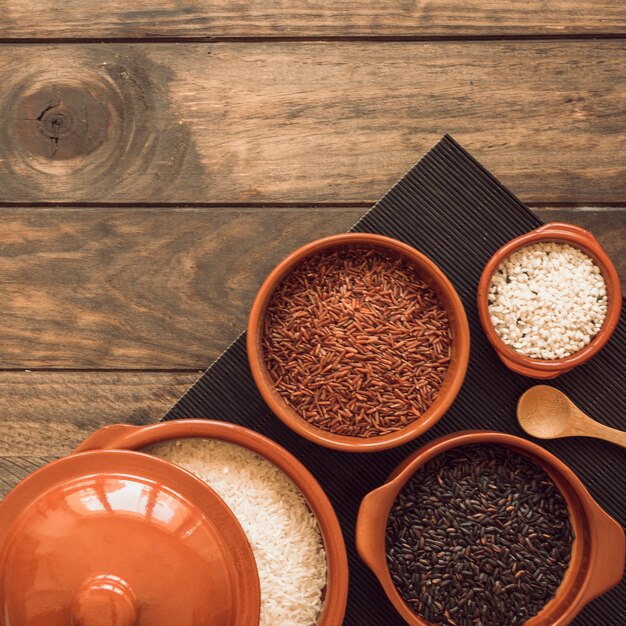 Diferentes tipos de cuencos de granos de arroz en mantel sobre la mesa de madera