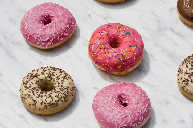 Diferentes tipos de donuts en mármol con textura de fondo