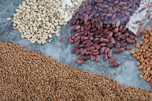 Diferentes tipos de frijoles crudos sobre mármol.