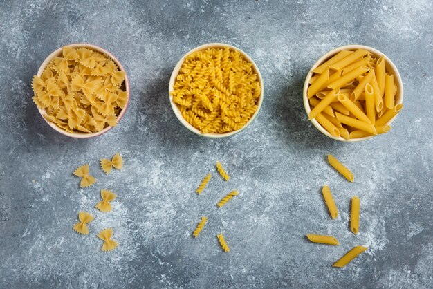 Diferentes tipos de macarrones crudos sobre mármol.