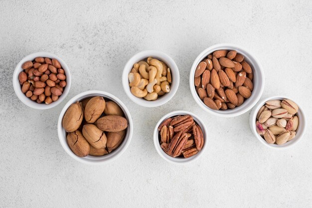 Diferentes tipos de nueces en tazones blancos pequeños y grandes