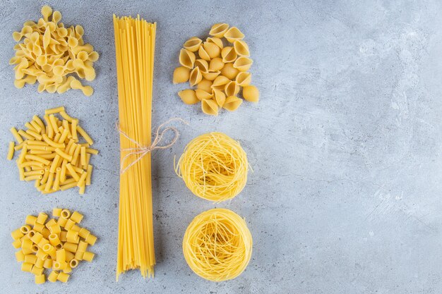 Diferentes tipos de pasta seca cruda sobre un fondo de piedra.