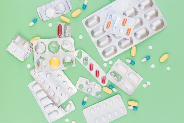 Diferentes tipos de píldoras médicas en blíster con fondo verde