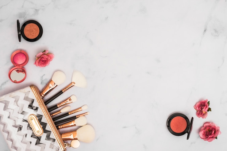 Foto gratuito diferentes tipos de pinceles de maquillaje en la bolsa con polvos faciales compactos y flores color de rosa sobre fondo blanco