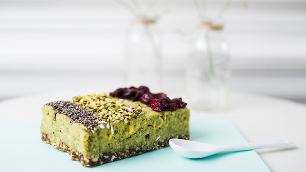 Diferentes tipos de rebanada de pastel con chia; Aderezos de pistachos y arándanos secos en una tabla de cortar