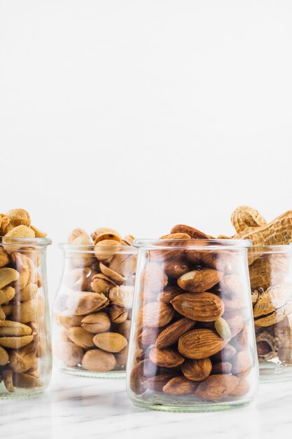 Diferentes tipos de tarros de comida de nueces en superficie de mármol