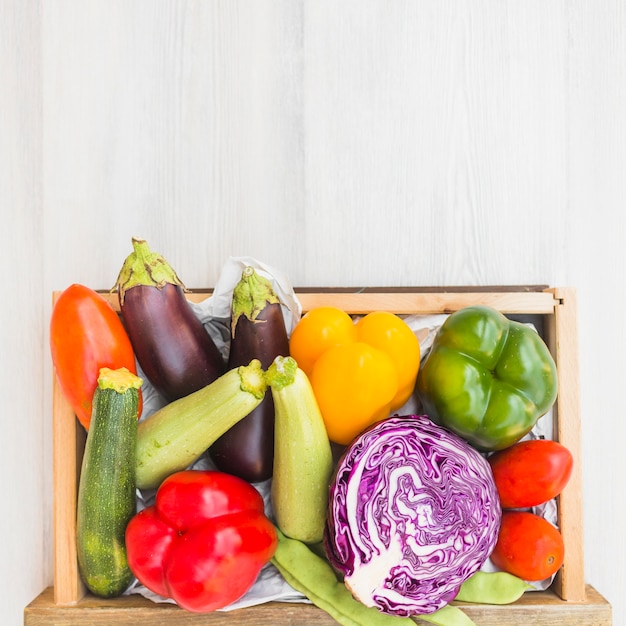 Diferentes tipos de verduras en contenedor sobre fondo de madera