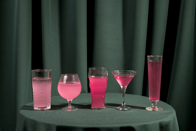 Diferentes vasos llenos de líquido rosa sobre mesa.