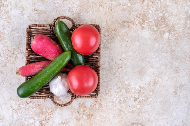 Foto gratuita diferentes verduras en una canasta de mimbre, sobre la mesa de mármol.