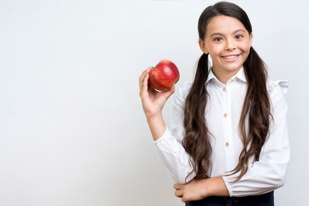 Diligente colegiala hispana comiendo manzana