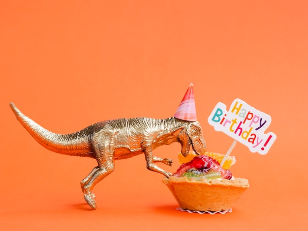 Dinosaurio de juguete comiendo dulces de cumpleaños