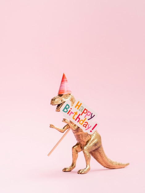 Dinosaurio de juguete divertido con cartel de feliz cumpleaños