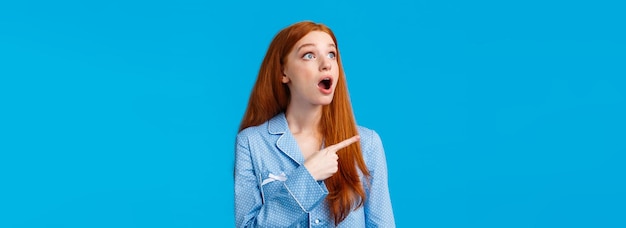 Foto gratuita dios mío, échale un vistazo sorprendida y emocionalmente impresionada, la mujer pelirroja se queda boquiabierta mirando la esquina superior izquierda