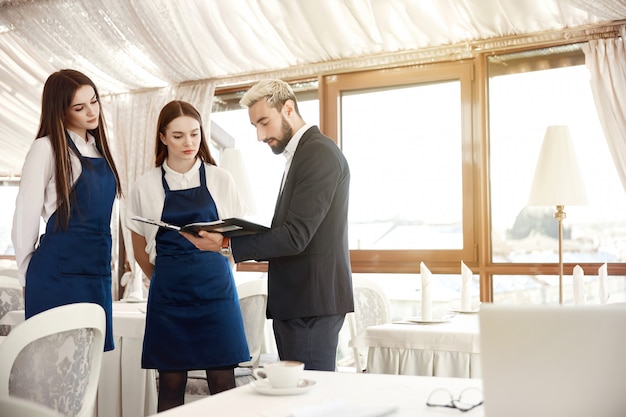 El director de un restaurante está dando instrucciones de trabajo a las camareras.