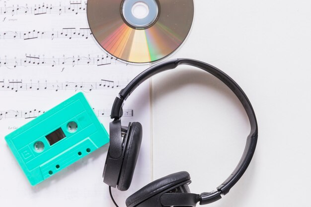 Disco compacto; Cassette y auriculares en nota musical sobre fondo blanco