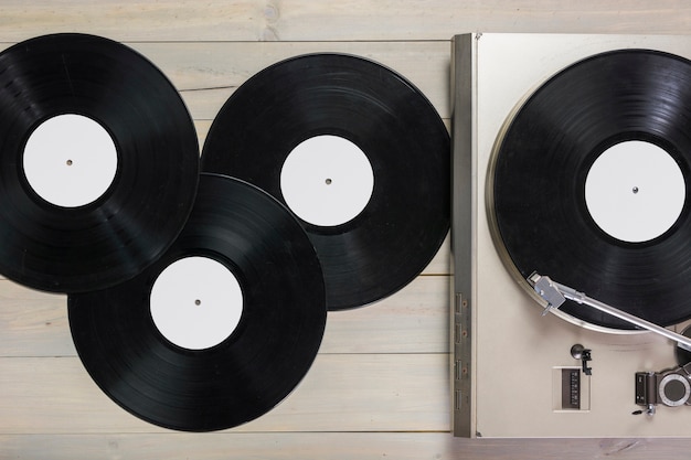 Discos de vinilo y tocadiscos giradiscos en mesa de madera.