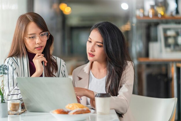 Discusión de reunión informal de agencia creativa femenina asiática trabajando con trabajo de café de computadora portátil desde casa con un cliente compañero de trabajo mujer joven asiática con ventana y agua gota de lluvia lloviendo fondo