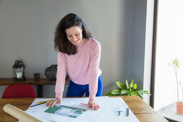 Diseñador de apartamentos exitoso positivo trabajando con plano