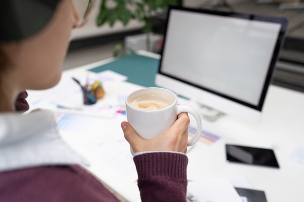 Diseñador femenino sosteniendo una taza con café