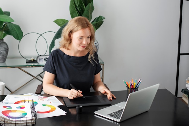 Diseñador de logotipo femenino trabajando en su oficina en una tableta gráfica