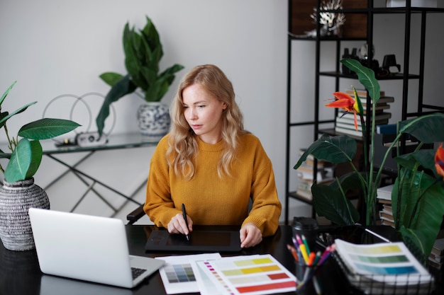 Diseñador de logotipo femenino trabajando en su tableta conectada a una computadora portátil
