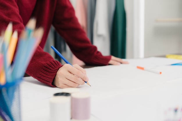 Foto gratuita diseñador de moda femenina asiática hermosa profesional trabajando con bocetos de tela